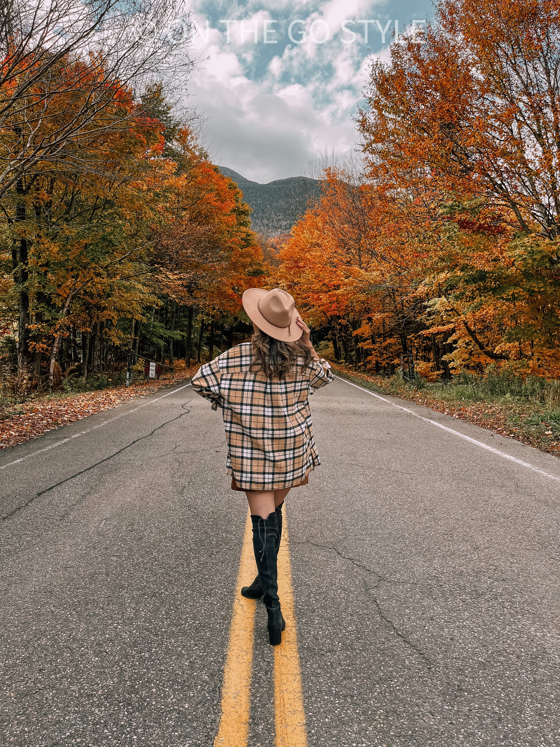 Picture of back of hat and plaid jacket in middle of winding road in Stowe